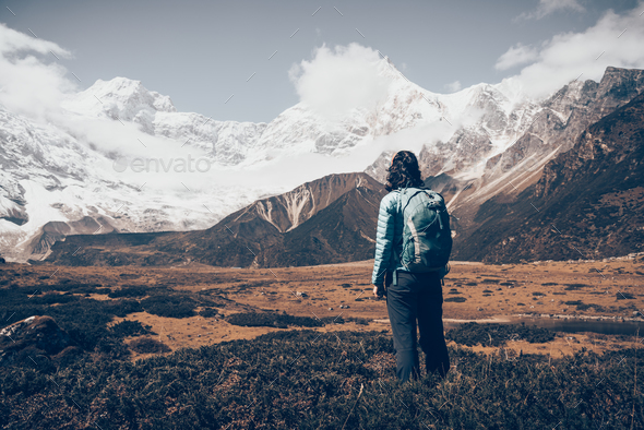 Standing young woman with backpack and mountains - Stock Photo - Images