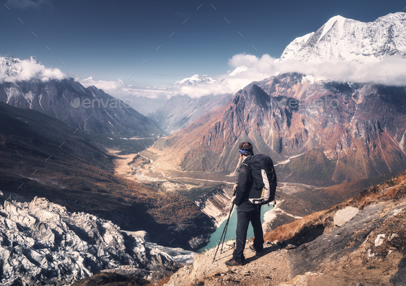 Man with backpack on the mountain peak at sunset - Stock Photo - Images
