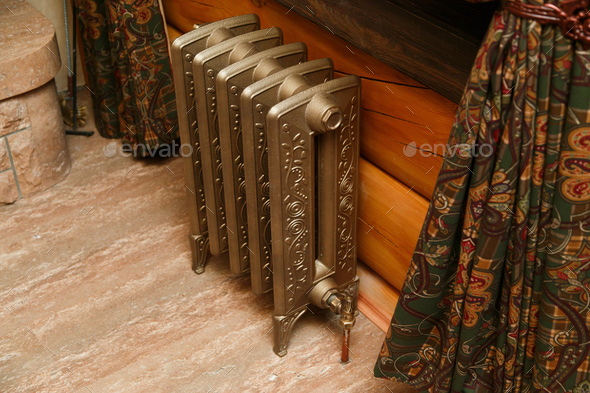 Retro styled cast iron radiator with valve and copper pipe Stock Photo by Vladdeep