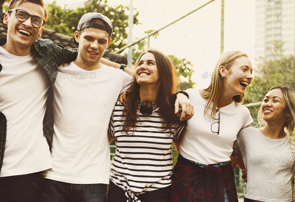 Smiling happy young adult friends arms around shoulder outdoors