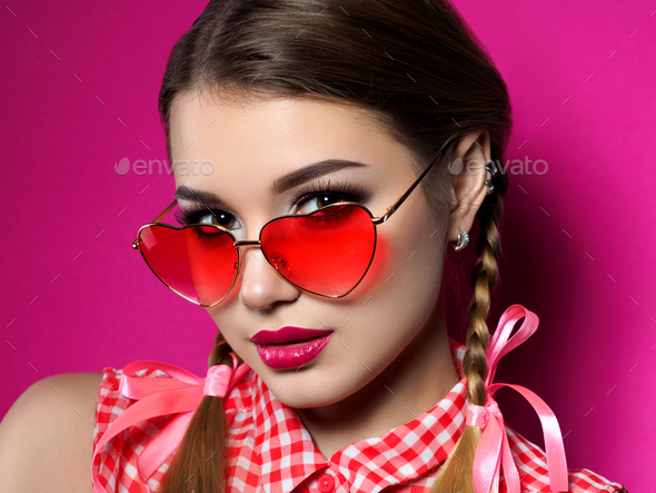 Young woman looks over heart shaped glasses - Stock Photo - Images