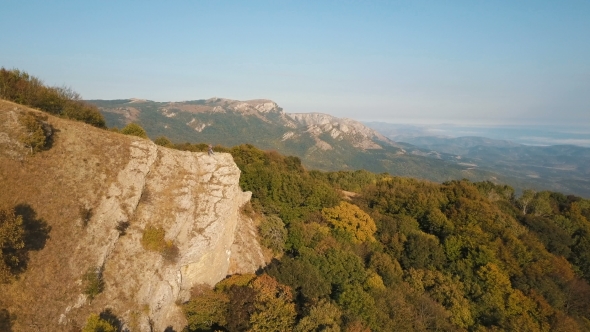 Aerial Flight over Young Couple Standing on Cliff Edge of Epic Alpine Mountain alt