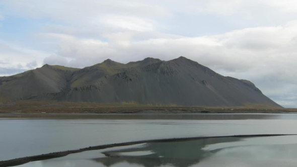 Calm and Dramatic Icelandic Landscape with Dark Mountains and Wide River in Cloudy Weather