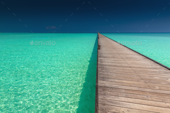 Wooden long jetty over lagoon with amazing clean azure water Stock Photo by mvaligursky