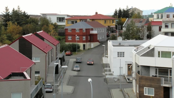 Small Icelandic Street with Houses, Parked Car in Autumn Day, One Red Car Is Moving