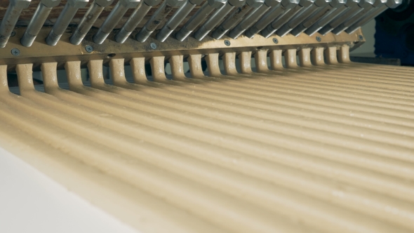 Straight Lines of Sweet Cream Flowing From a Paste-making Machine alt