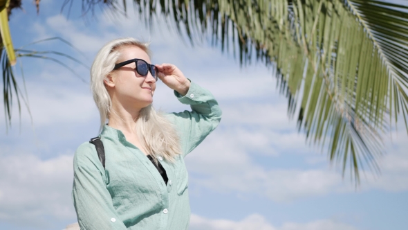 Happy Caucasian Woman with Long Blonde Hair in Sunglasses and Green Shirt Standing and Smiling Near