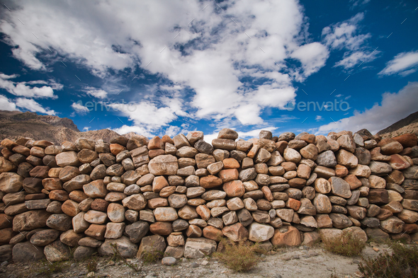 The stone wall under the cloudy sky. Background. - Stock Photo - Images