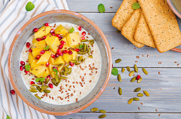 Tasty and healthy oatmeal porridge with mango, pomegranate and seeds - Stock Photo - Images