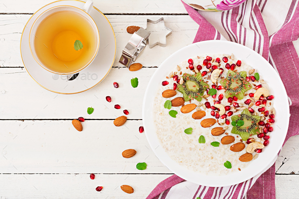 Tasty and healthy oatmeal porridge with kiwi, pomegranate and seeds - Stock Photo - Images