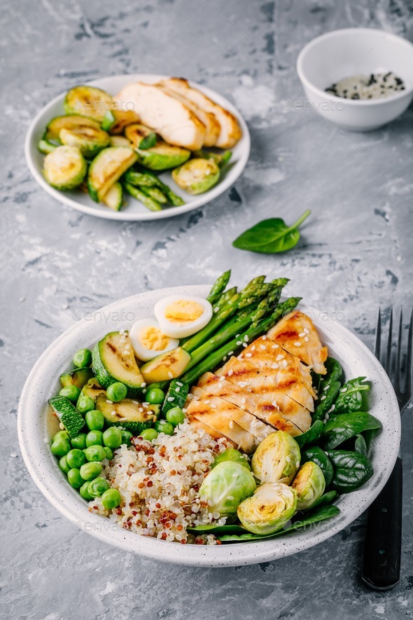 Bowl with chicken and quinoa, spinach, egg, zucchini, asparagus, Brussels sprouts and green peas Stock Photo by nblxer