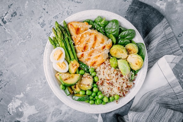 Bowl with chicken and quinoa, spinach, egg, zucchini, asparagus, Brussels sprouts and green peas Stock Photo by nblxer