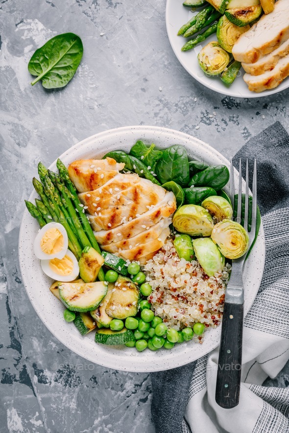 Healthy bowl with chicken and quinoa, spinach, egg, zucchini, asparagus, Brussels sprouts and peas Stock Photo by nblxer