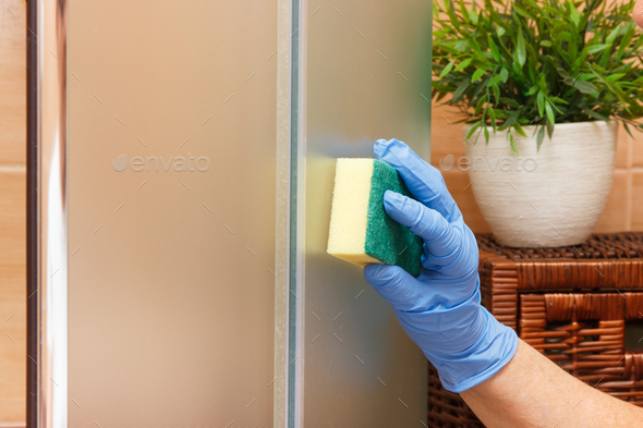 Hand of senior woman using sponge and cleaning shower cabin in bathroom, household duties concept - Stock Photo - Images