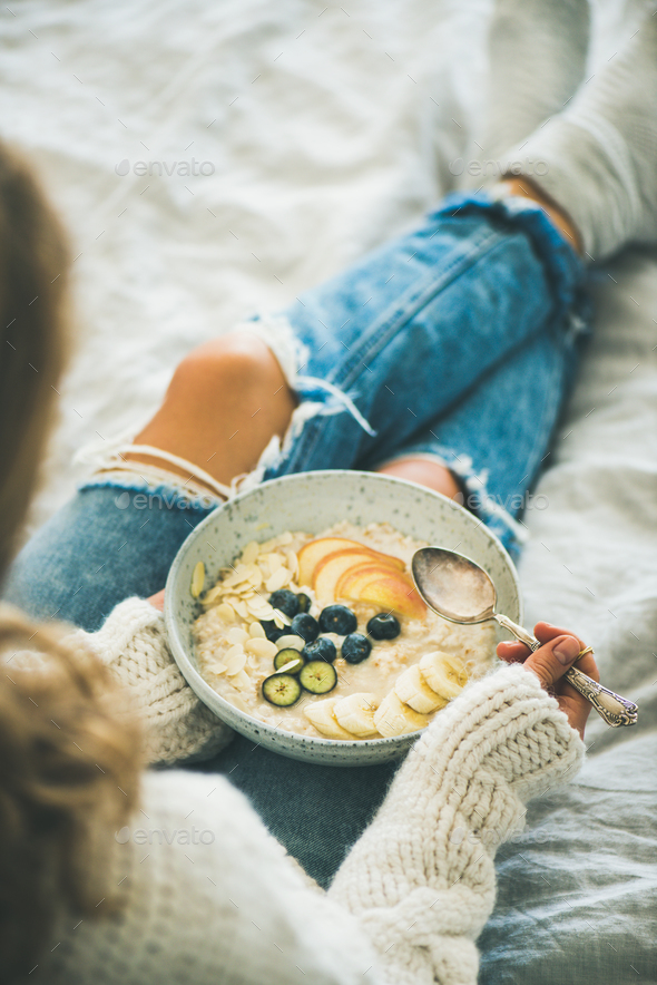 Woman in shabby jeans and sweater eating vegan breakfast - Stock Photo - Images