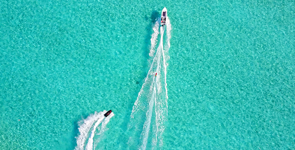Jet and Waterskier Racing Out From Tropical Island Into Deep Blue Water