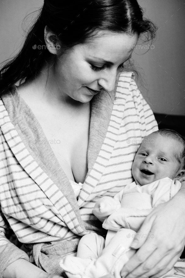 Young woman holding a newborn baby in her arms. Happy family. Black and white. Stock Photo by Determined