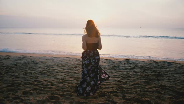 Camera Follows Happy Excited Female Traveler in Beautiful Dress Running To Coming Ocean Wave To alt