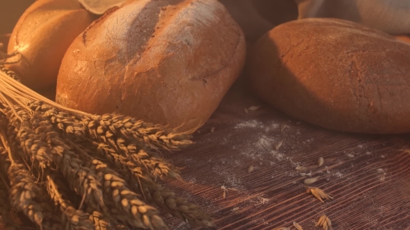 Handmade Tasty Bread Lying on Burlap on the Wooden Table with Flour, Wheat and Ears of Wheat