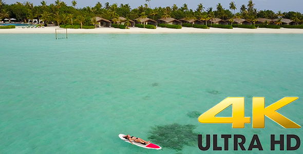 Girl Relaxing on Paddle Board in Front of Luxurious Private Island Resort