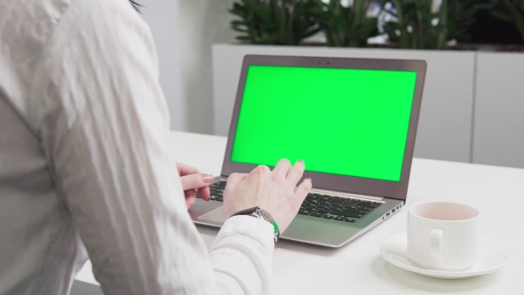 Woman's Hands Using Laptop with Green Screen on Table