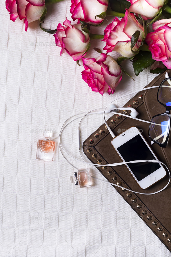 female clutch with phone, headphones and Perfume bottles with flowers - Stock Photo - Images