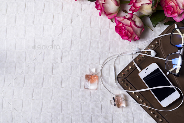 female clutch with phone, headphones and Perfume bottles with flowers - Stock Photo - Images
