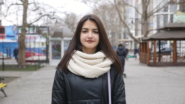 A Charming Girl Strolls in a City Street and Smiles Happily in Winter in Slo-mo