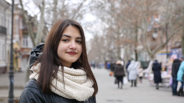 A Cheerful Girl Stands in a Park Alley and Smiles Slightly in Winter in Slo-mo