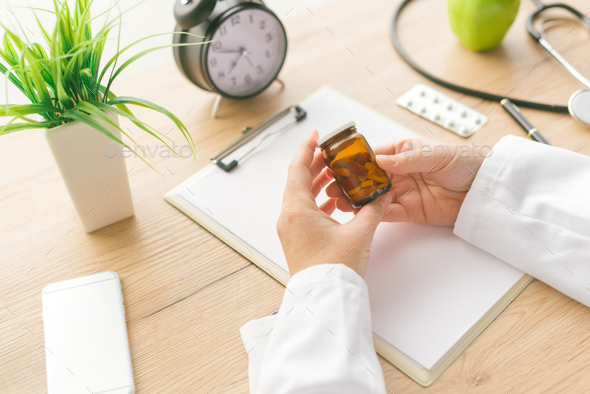 Female doctor holding unlabeled bottle of various pills and medi - Stock Photo - Images