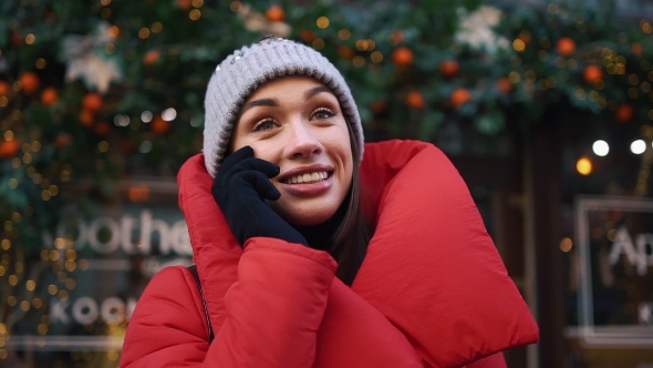 Charming Woman Looks Happy Talking on the Phone While She Stands on the Cold Winter Street alt