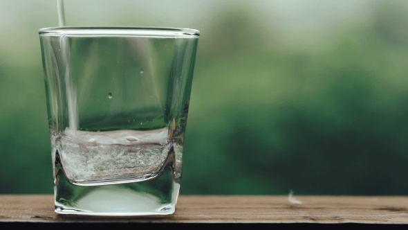 Water Pouring in Glass on Wooden Table. Pouring Drink in Glass.  of Pouring Water.