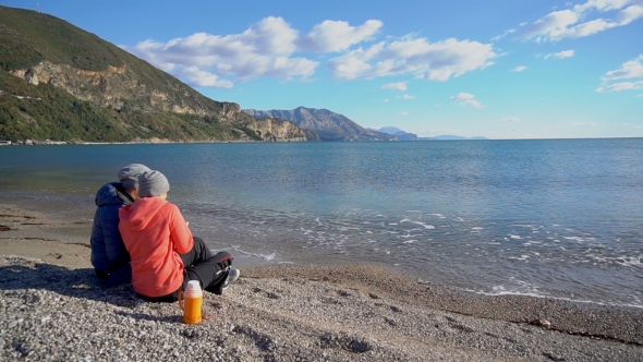 Back View of Romantic Couple Sitting on the Beach and Look at the Sea