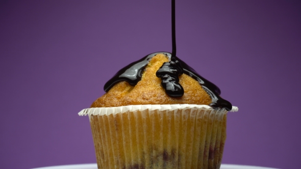 Cupcake Pouring Melted Chocolate Syrup on a Plate