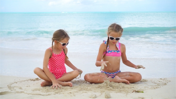 Adorable Little Girls Playing with Sand on the Beach. Kids Sitting in Shallow Water and Making a alt