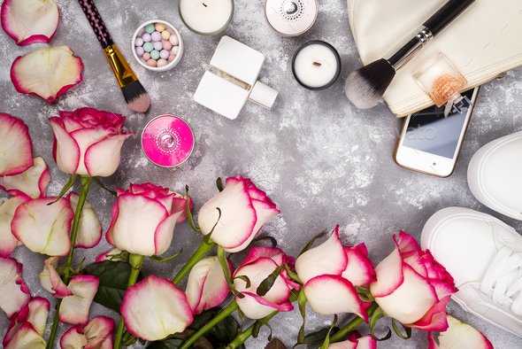 Bouquet of roses with cosmetics in perfume, phone and sneakers on a gray background with copy space - Stock Photo - Images