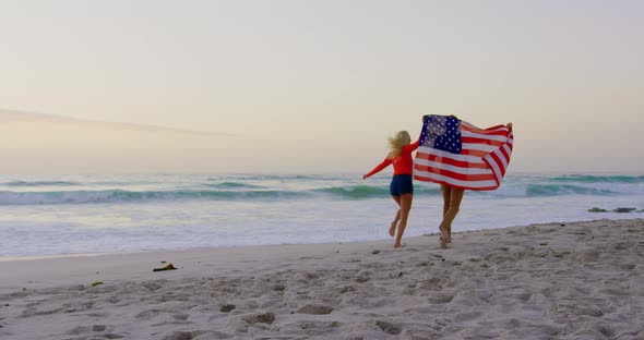 Couple running with American flag at beach 