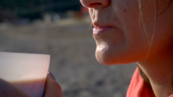 Female Mouth Tasting Coffee at the Beach