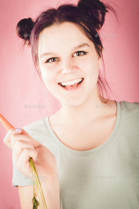 Smiling young teenage girl holding vitamin-rich carrot and looki - Stock Photo - Images