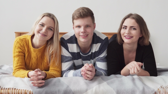 Group of Happy Teenagers Lying on Bed and Smiling