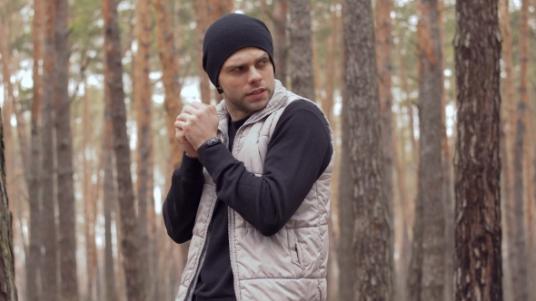 Young Guy Blows on His Hands Because He Feel Cold During Training in the Forest alt