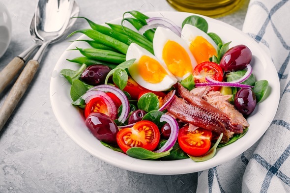 nicoise salad with tuna, anchovies, eggs, green beans, olives, tomatoes, red onions and salad leaves Stock Photo by nblxer