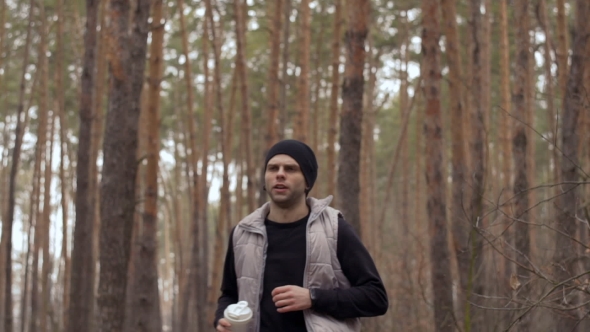 Young Guy Stop To Drink Water During Morning Jogging alt