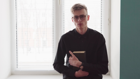 Young Religious Man Holding a Bible and Looking at the Camera alt