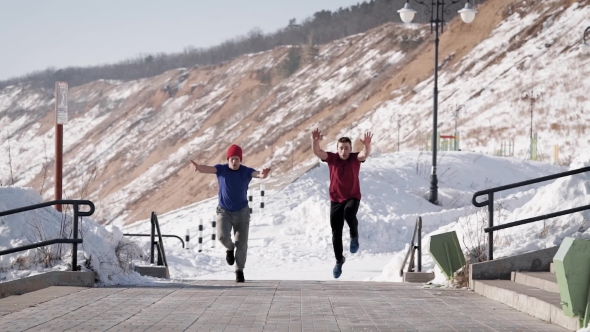 Two Athletes Are Doing a Flips Synchronously and in Parallel in a Park in Sunny Winter Day, Moving alt