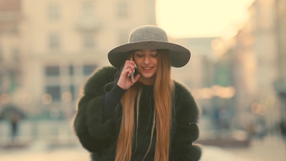 Young Woman in a Bright Sunlight Uses Her Phone Smile Talks in the Phone alt