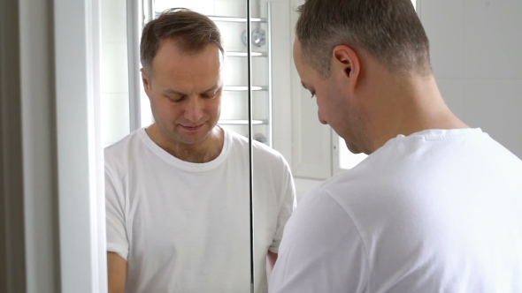 Man with a Rubber Glove Cleans a Sink in the Bathroom alt