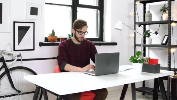 Serious Man Typing on the Laptop Sitting in Office alt