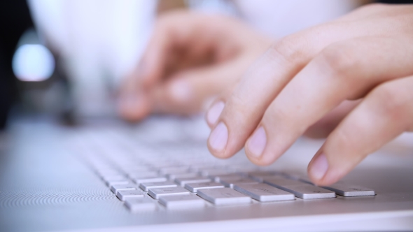 Hands Work on the Laptop Keyboard. In the Background, Work in the Office alt