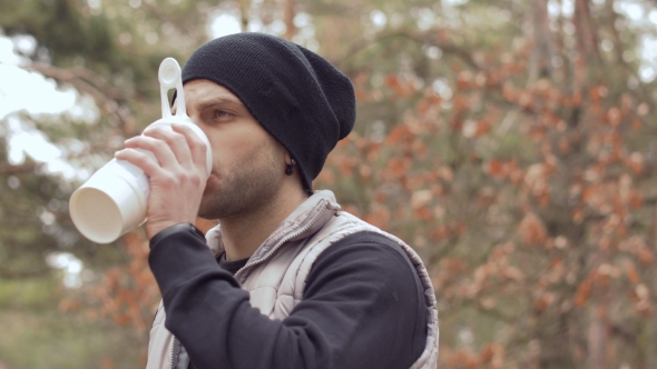 Young Man Drinks Water During Morning Running in the Forest alt